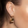 Gold iris petal hoop earrings showcased on a model's ear with a dragonfly stud earring.