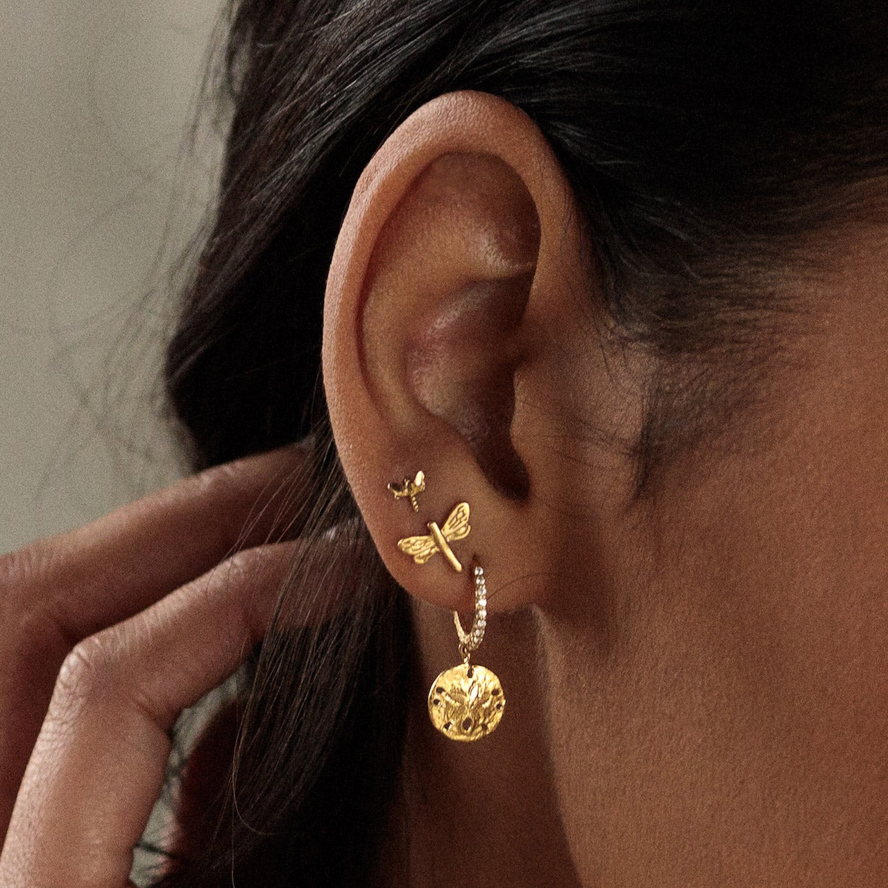 Gold Dancing Dragonfly Studs worn on ear, showcasing detailed design and elegant styling.
