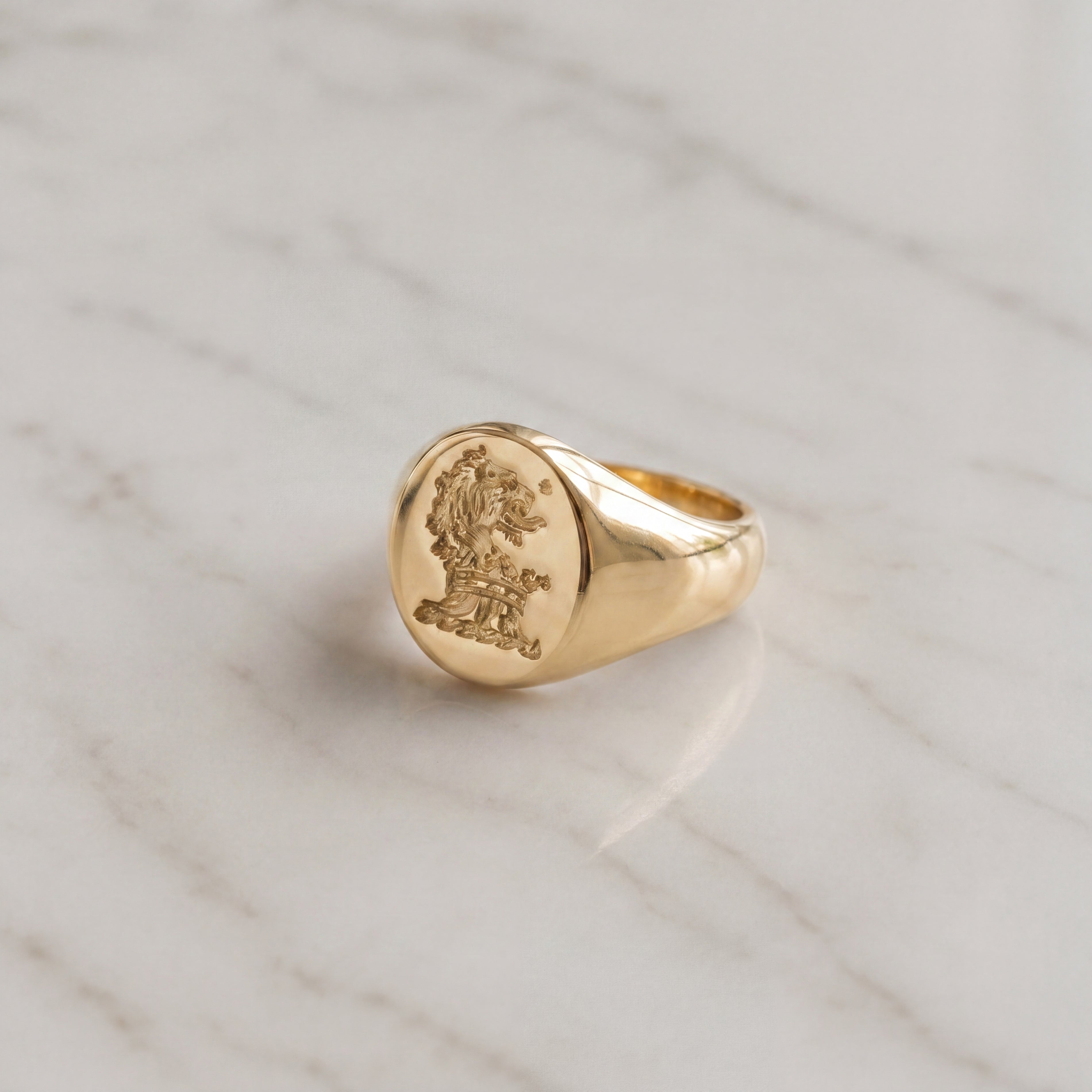 9ct gold signet ring featuring a detailed lion crest design on a polished gold surface.