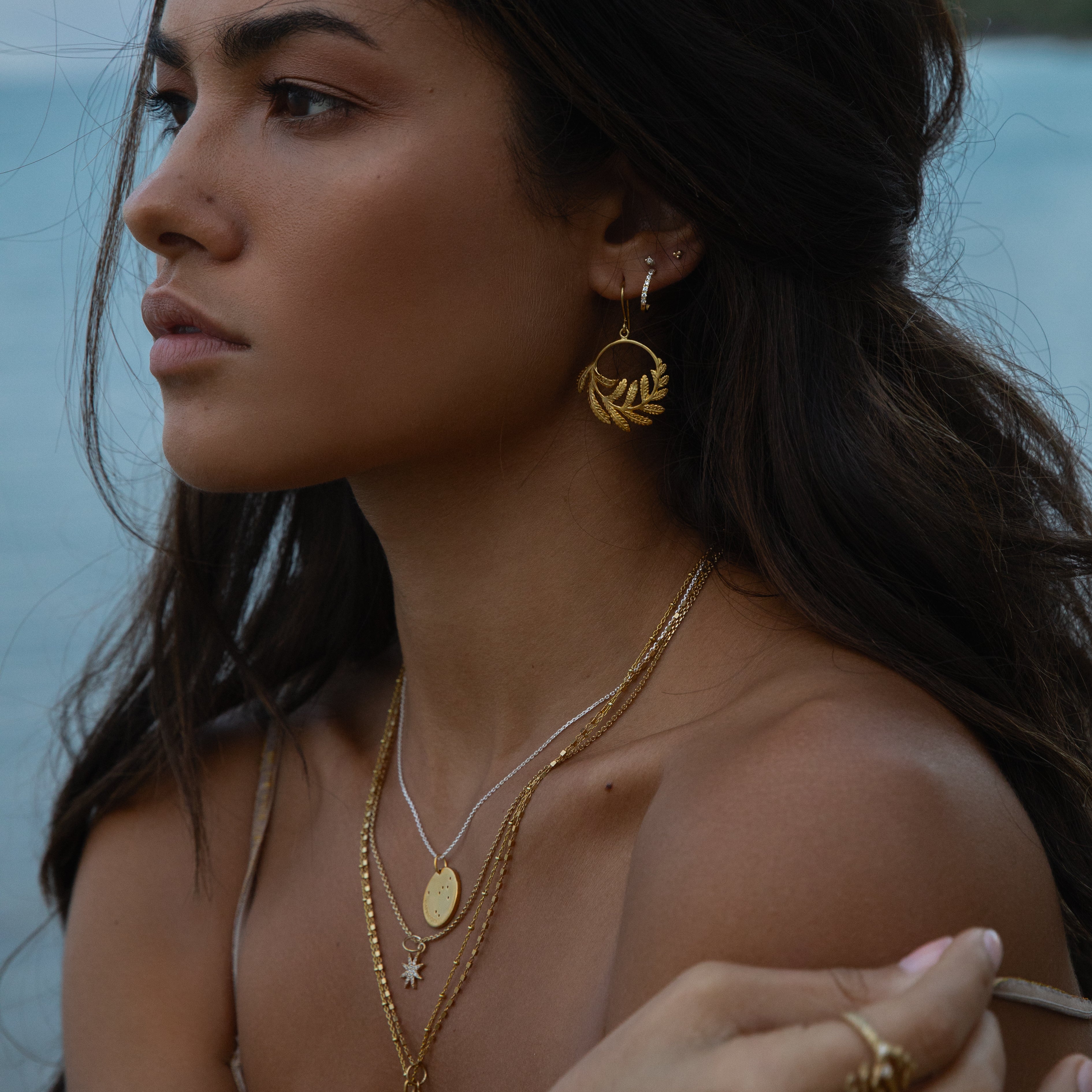 Gold fern hoop charm earrings on woman