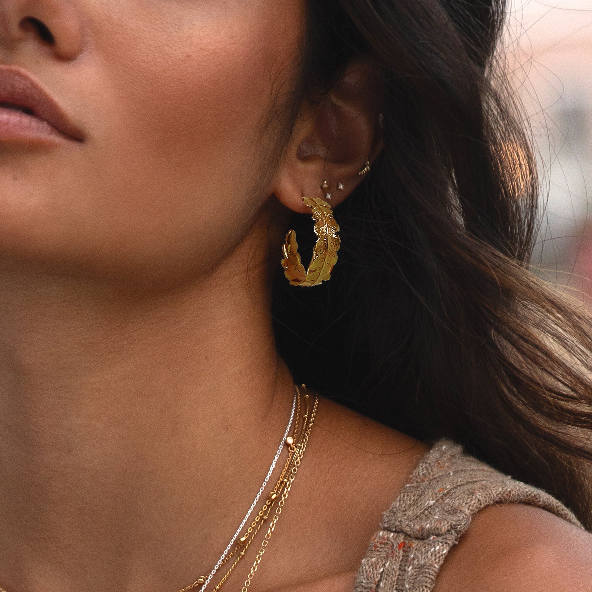 18ct gold plated fern hoop earrings worn stacked on womans ear 