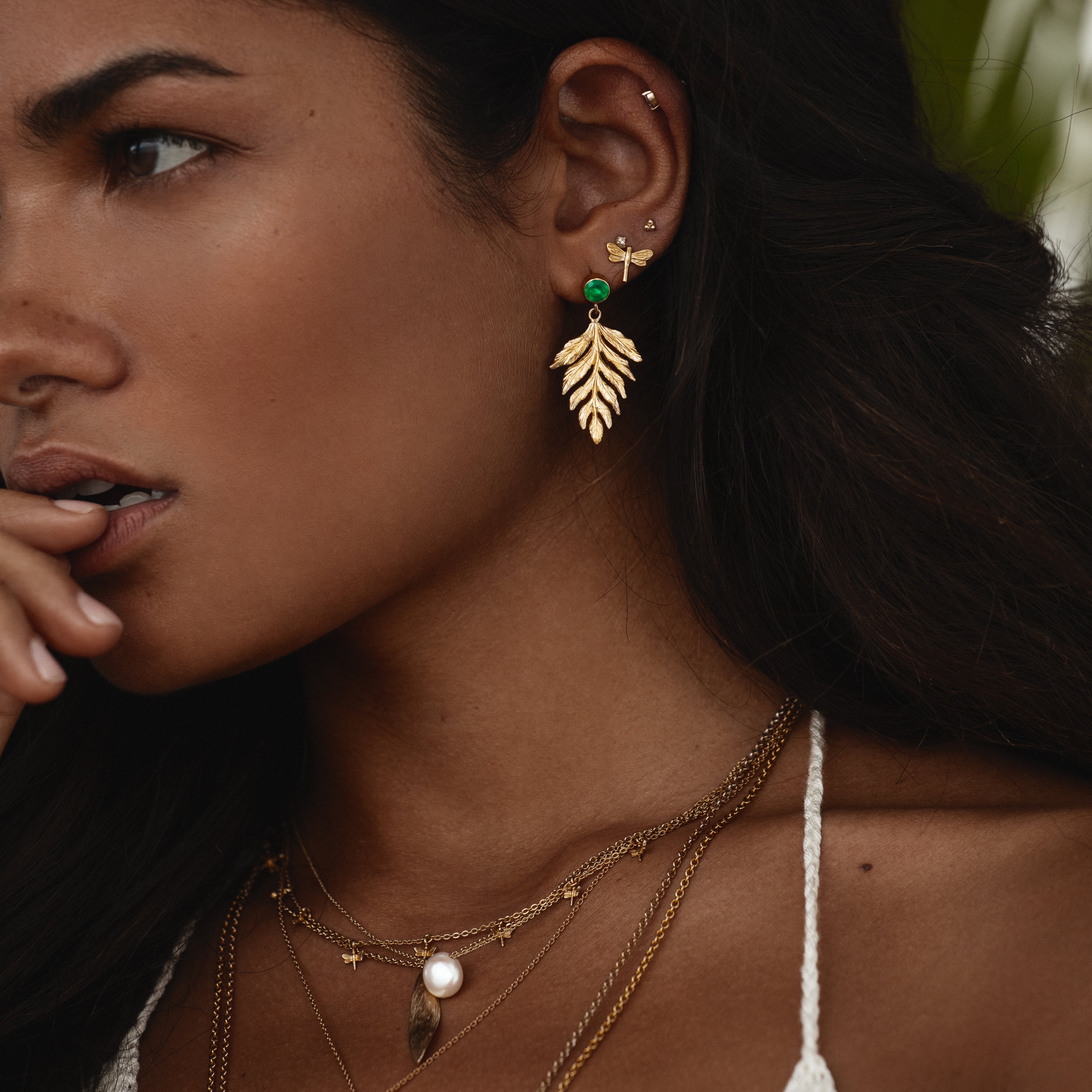 Model wearing gold green agate fern drop earrings, showcasing nature-inspired elegance and stylish details.