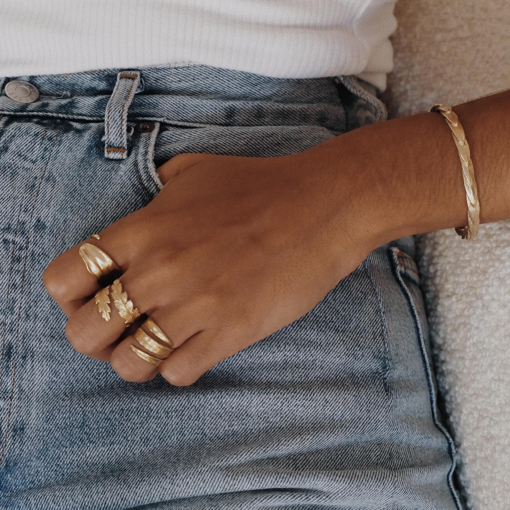Model wearing multiple rings and a bracelet, including the Gold Blade of Grass Ring, against a casual outfit.