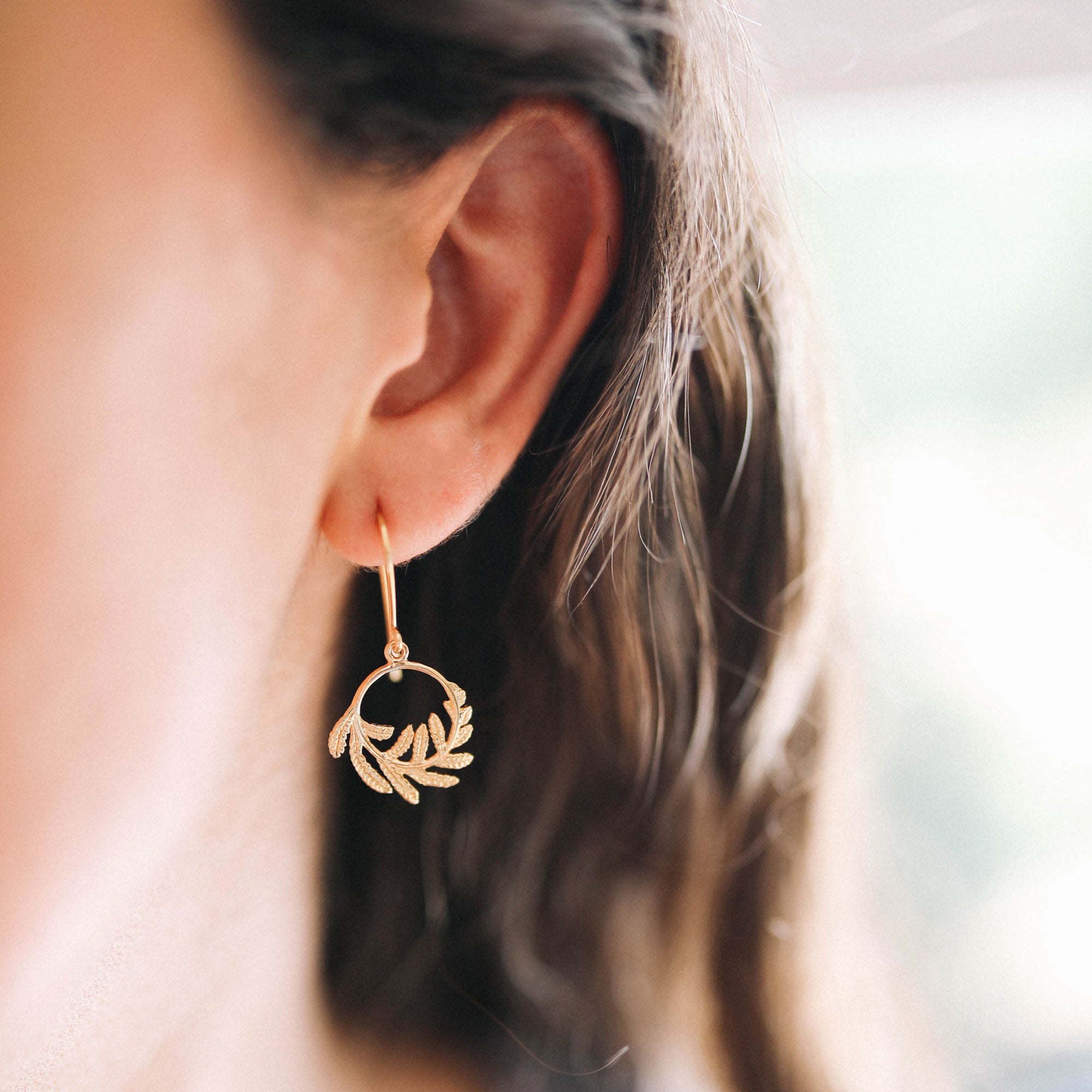 Gold Wee Fern Hoop Earrings showcased on a model's ear, featuring a delicate fern design in 18ct gold plated silver.