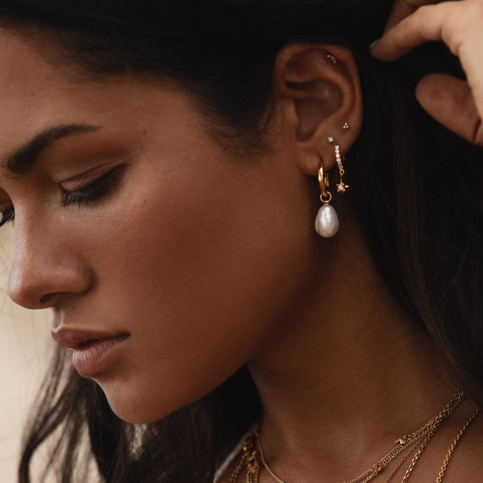 Gold mini hoop and pearl earrings worn by a model, showcasing contemporary elegance and chic style.