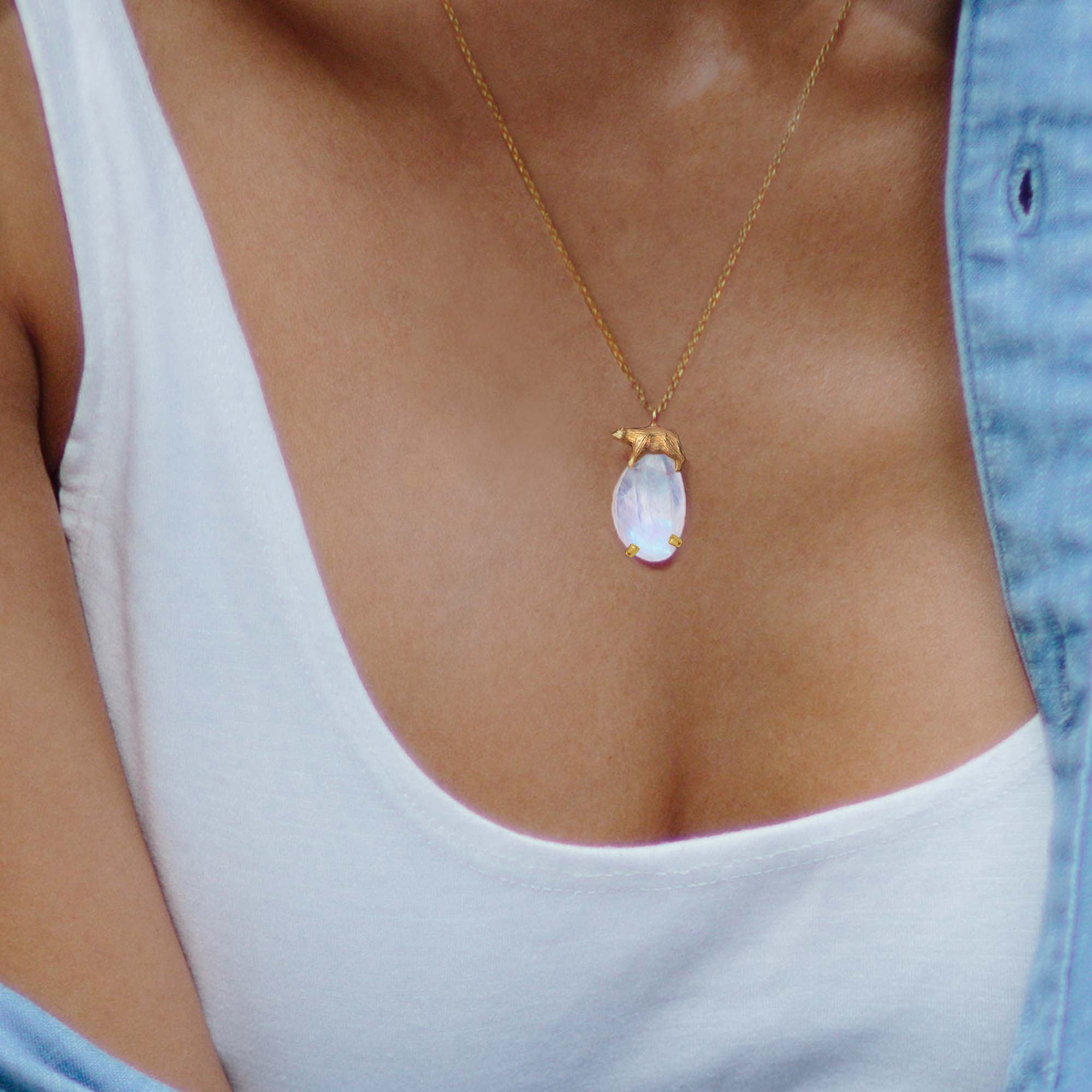Golden Polar bear and Moonstone Iceberg Pendant worn on a woman's neck, featuring rainbow moonstone and 18ct gold plating.