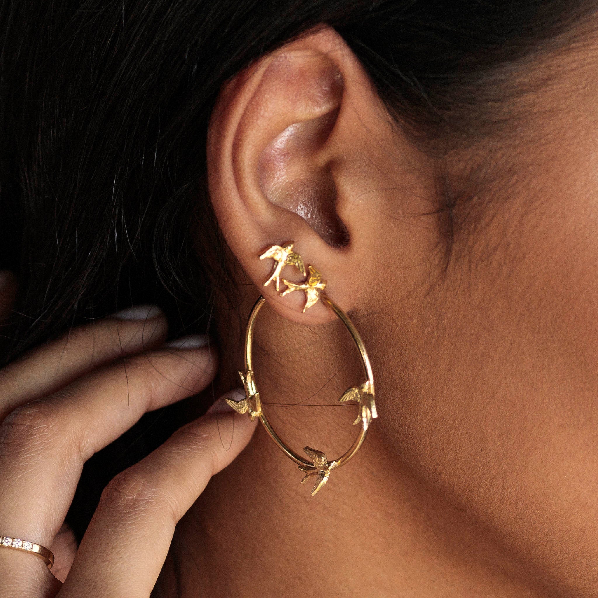 Gold Swallow Stud Earrings worn in an ear, showcasing eco silver design with swallows in flight.