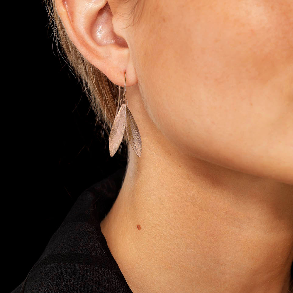 Close-up of a model wearing Rose Gold Double Leaf Earrings showcasing intricate feather details.